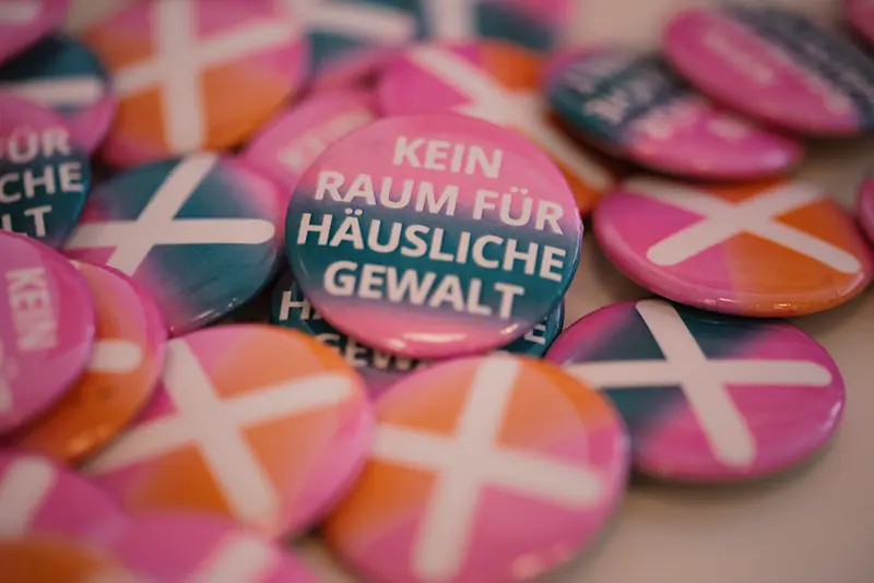 Buttons mit dem Slogan „Kein Raum für Häusliche Gewalt“ Buttons mit dem Slogan „Kein Raum für Häusliche Gewalt“